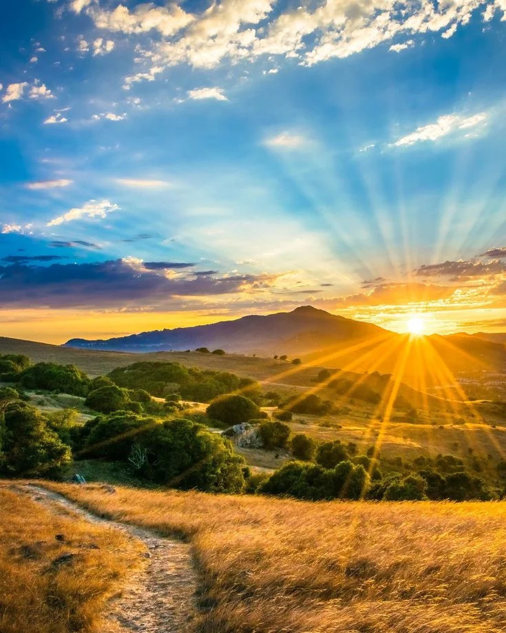 Sunrise Over An Open Field And Distant Hills